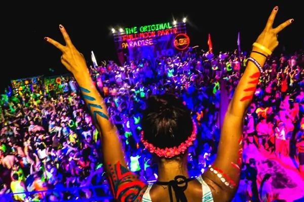 Crowd enjoying vibrant Full Moon Party in Koh Phangan with neon lights, music stage, and dancing atmosphere – Thailand nightlife festival